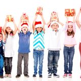 Excited children holding Christmas gifts with arms up - isolated over 