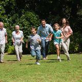 Happy multi generation family running towards camera in the park on su
