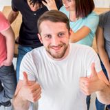 happy-young-man-standing-with-friends-showing-thumbup-gesture-looking-